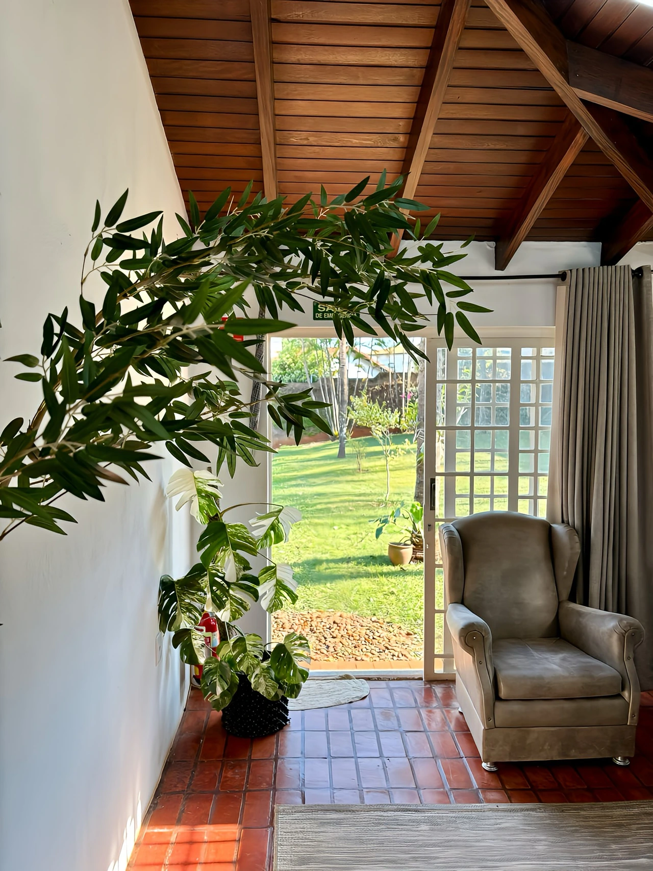 Ambiente da clínica com plantas, poltrona e vista para o jardim